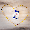 A bottle of 21st Century Norwegian Cod Liver Oil 400 mg softgels laying on a wood floor surrounded by softgels in the shape of a heart.