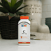 A bottle of 21st Century Vitamin C 1000 mg tablets sitting on a kitchen counter with a plant and a basket with a vintage milk jug in the background.