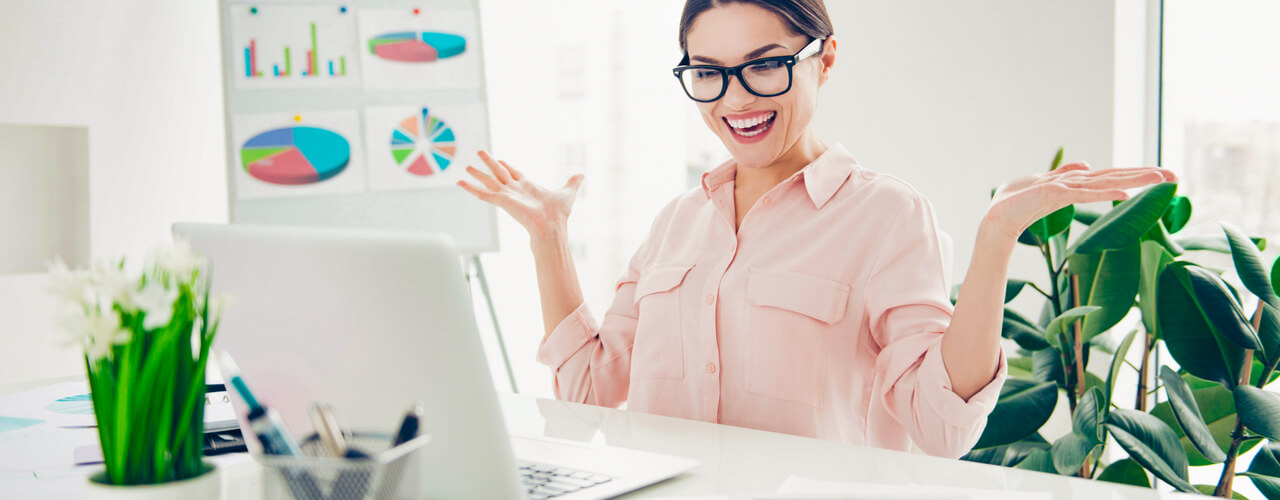 A girl sitting at her office desk smiling and looking happy while working.