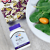 A bottle of 21st Century Co Q-10 200 mg rapid release softgels laying on a table next to a dinner plate of salad and a napkin.