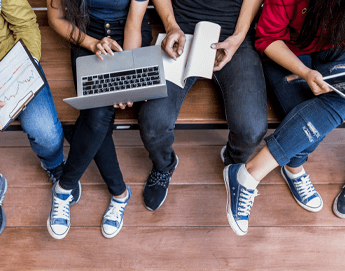 Top view of kids sitting with notebooks and computers.