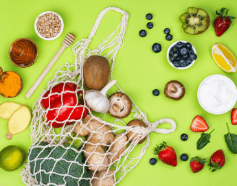 Assorted fruits and vegetables on a green background.