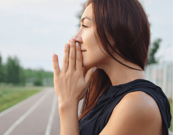 Side view of girl standing outside looking at sky with hands together as if praying.