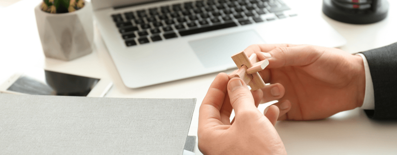 A closeup of hands holding wood puzzle pieces.