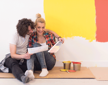 A couple sitting on the floor selecting paint swatches for a wall color.