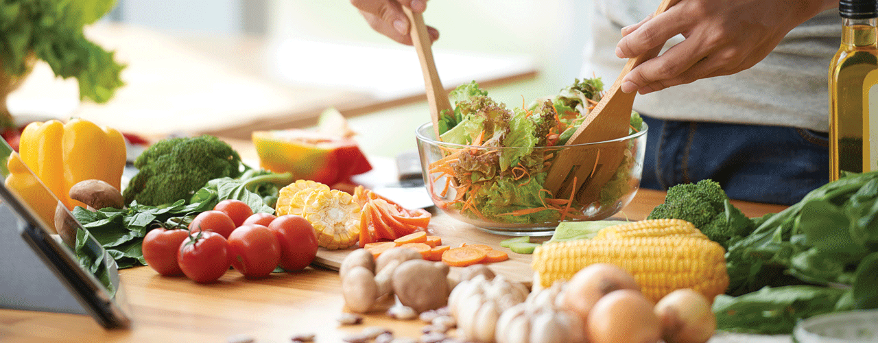 A person making a garden salad in the kitchen.