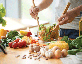 A person making a garden salad in the kitchen.