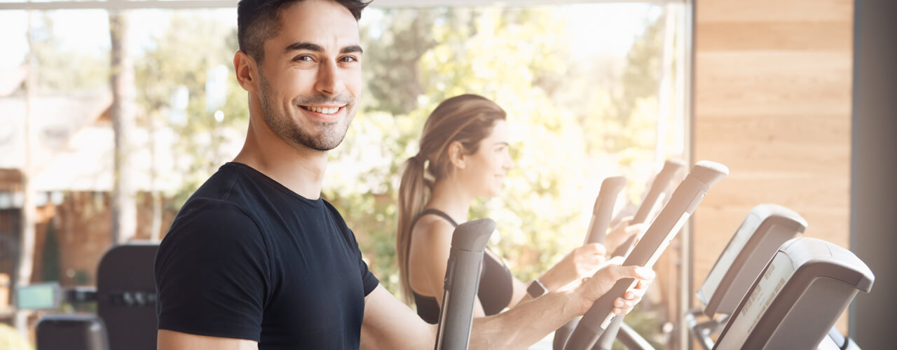 Workout room with a man and woman on ellipticals.