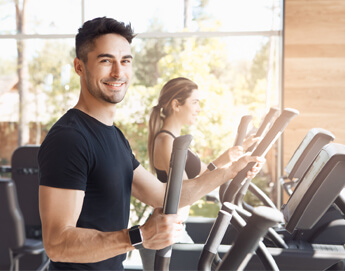 Workout room with a man and woman on ellipticals.