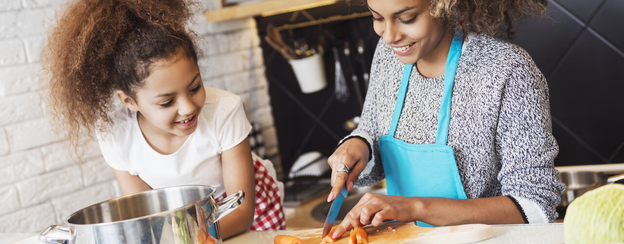 A mother and daughter cooking in the kitchen together.