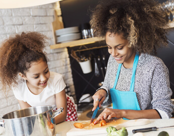 A mother and daughter cooking in the kitchen together.