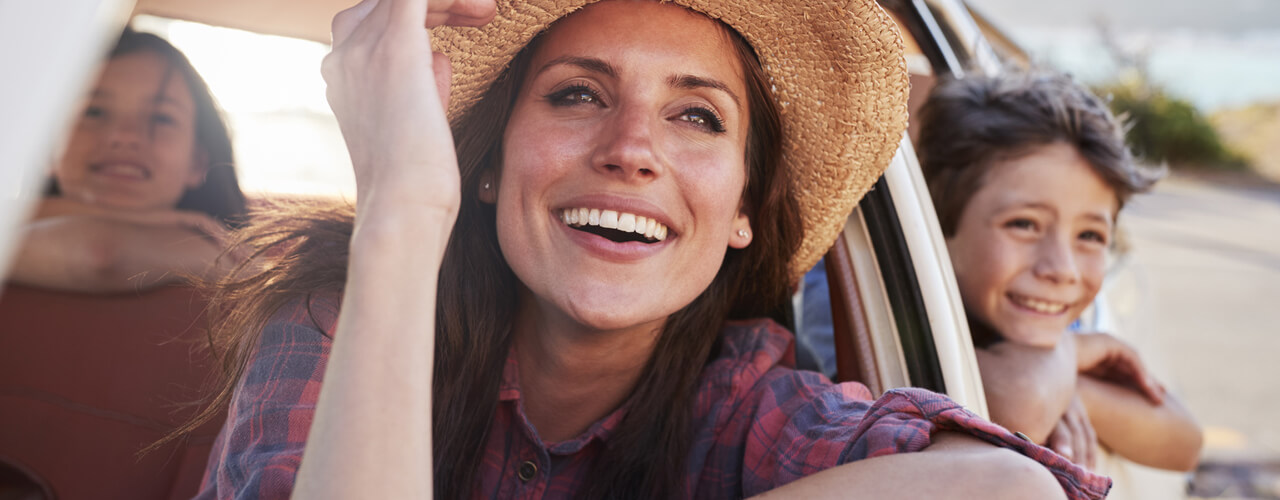 A happy family looking out the rolled down windows of a car.