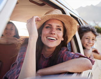 A happy family looking out the rolled down windows of a car.