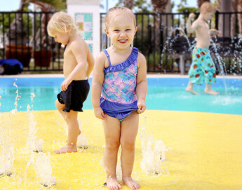 A group of young children playing at a splash pad.