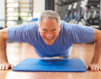 An older man in a gym doing push ups.