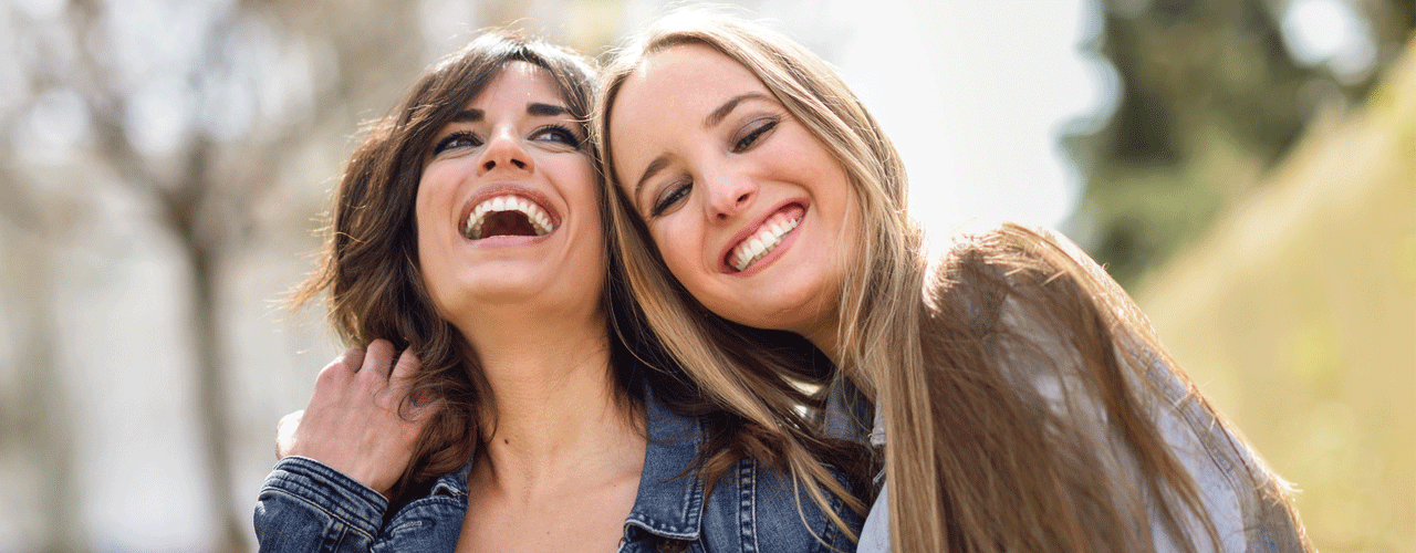 Two girl pals laughing and hugging.