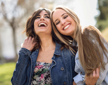 Two girl pals laughing and hugging.