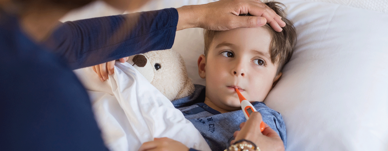 A mom taking her sons temperature while he lays in bed.