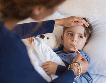 A mom taking her sons temperature while he lays in bed.