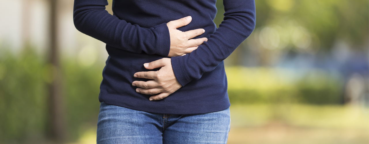 A front view of a girl holding her abdomen.