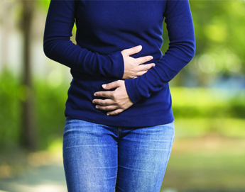 A front view of a girl holding her abdomen.