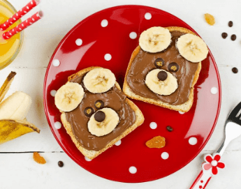 Peanut butter toast with bananas on top in the shape of a bear's face.