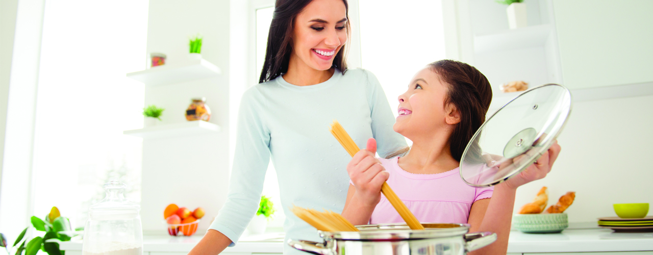 Mom and daughter cooking together in the kitchen.