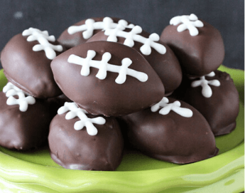 A plate full of chocolate covered treats in the shape of a football.