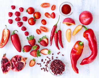 Red colored summer produce like peppers, chilis, tomatoes, pomegranate, raspberries and strawberries.