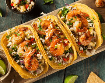 Delicious looking shrimp tacos on wood plank table top.