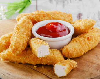 A delicious stack of chicken tenders next to a cup of ketchup.