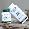 A bottle of 21st Century Mega Multi Men's Multivitamin and Multimineral tablets leaning on a bottle of 21st Century Milk Thistle Extract vegetarian capsules on a piece of old wood..