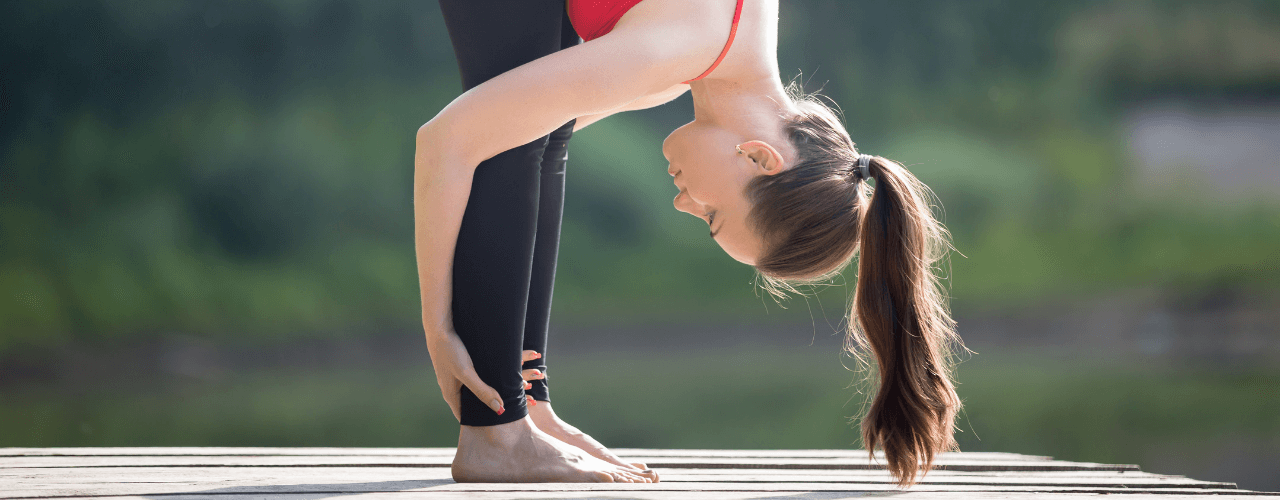 A young girl outside on a deck holding a yoga pose.