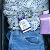 A bottle of 21st Century DHEA 25 mg capsules laying on a blouse and pair of jeans.